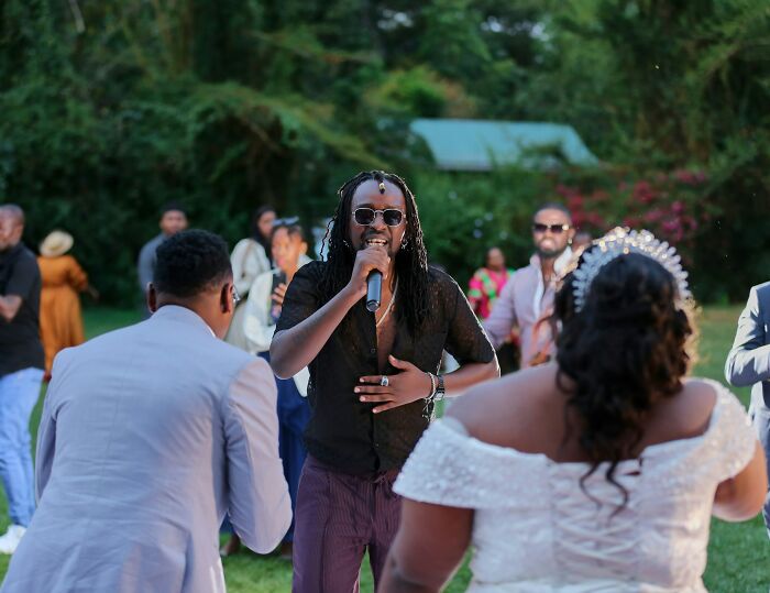 Man with sunglasses and microphone entertaining at an outdoor wedding, capturing trashy and tacky wedding stories atmosphere.