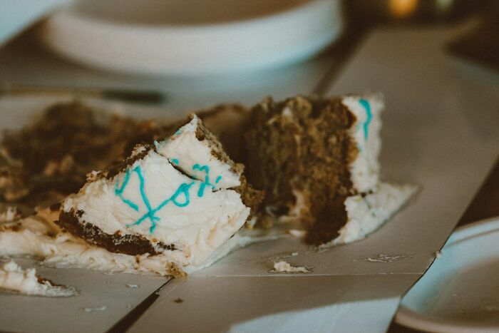 Partially eaten wedding cake pieces on a table, symbolizing guests witnessing a future breakup at a wedding event.