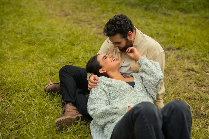 Couple sharing a joyful moment lying on grass, illustrating how random life decisions can lead people to the right place.