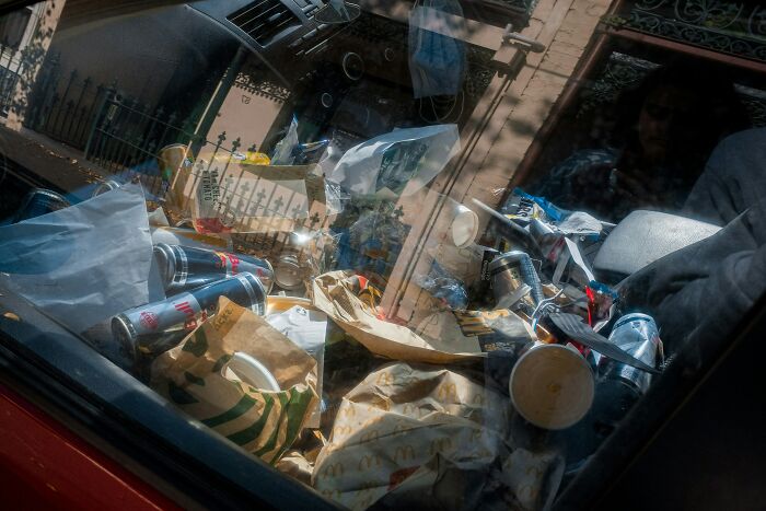 Cluttered car interior with trash and fast food wrappers reflecting red flags and instant regret on a disastrous first date.