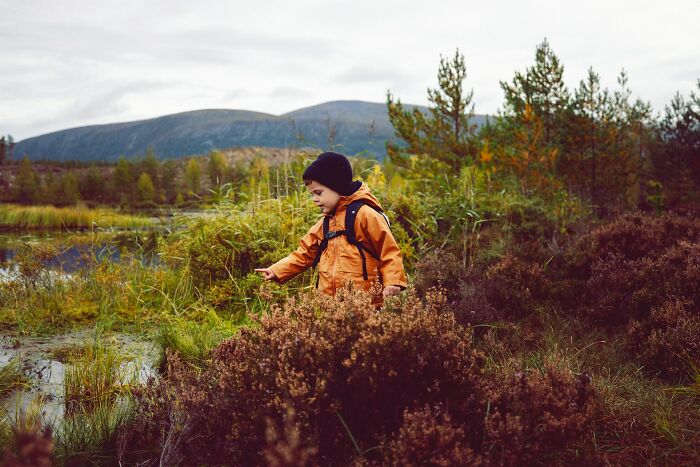 Child in orange jacket exploring outdoors, illustrating kids have no survival instincts in nature settings.