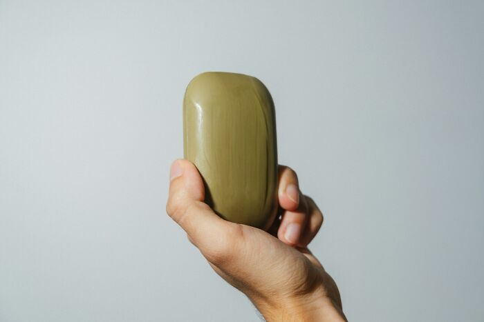 Hand holding a green bar of soap, representing normal family activities people now find bizarre.
