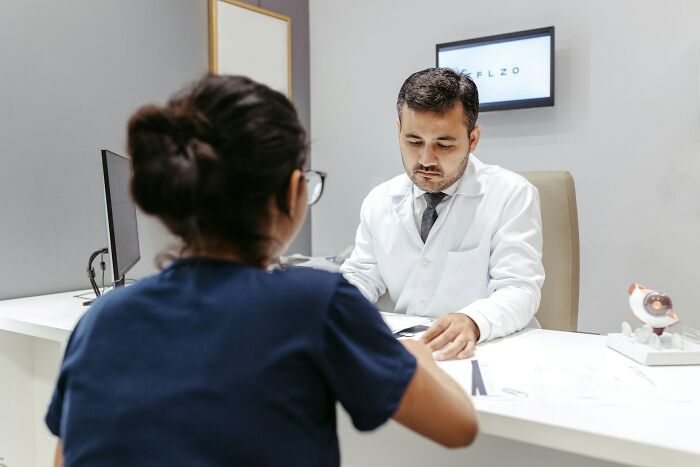 Gynecologist consulting a female patient in a clinical setting, reviewing medical documents during appointment.