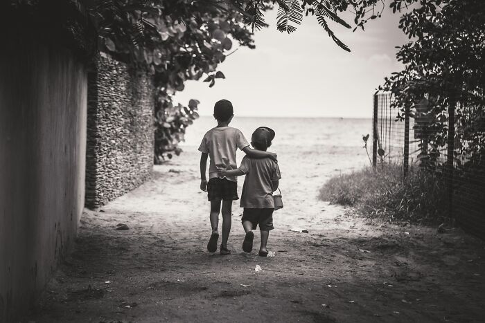 Two young boys walking arm in arm down a path near the beach, symbolizing family and DNA test discoveries.