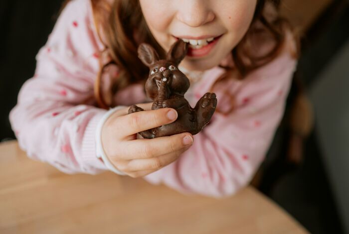 Child holding a chocolate bunny close to their mouth, illustrating parenting tips and tricks for engaging kids.