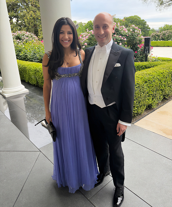 Smiling woman in a lavender gown and man in a tuxedo, MAGA figures at the White House.