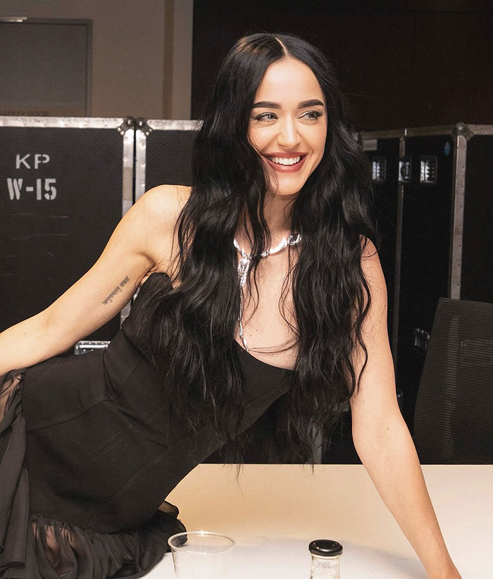 Woman with long black hair smiling, wearing a black dress, related to former club manager revealing misconduct claims. Woman with long black hair smiling, wearing a black dress, related to former club manager revealing misconduct claims.