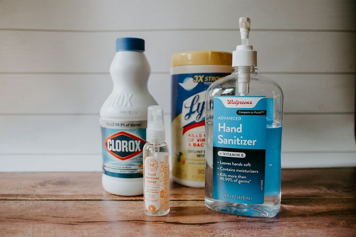 Various disinfectants including Clorox bleach, Lysol wipes, and hand sanitizer on a wooden surface showing kids’ lack of survival instincts.