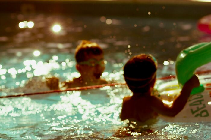 Two children playing in a swimming pool at night, illustrating childhood moments with no survival instincts involved.