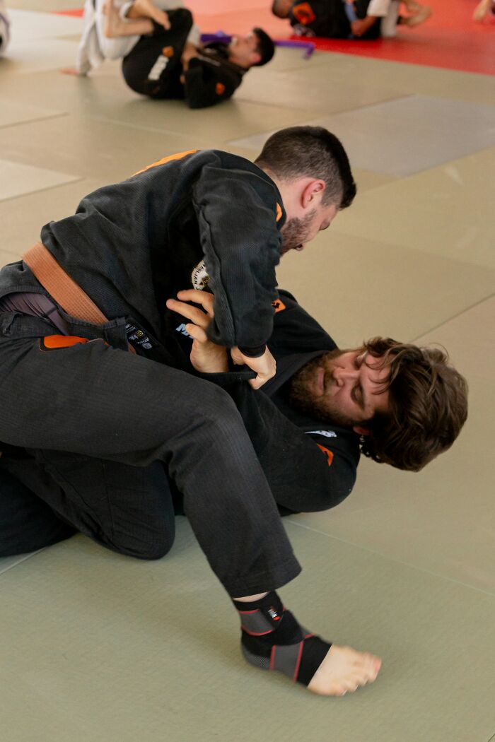 Two men practicing Brazilian jiu-jitsu grappling on mats, illustrating challenges similar to dealing with former bullies.