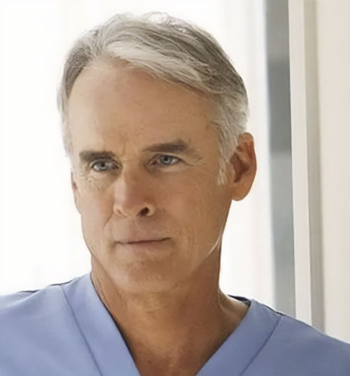 Middle-aged man in light blue shirt looking thoughtful, representing how the cast of Lost aged over 20 years.