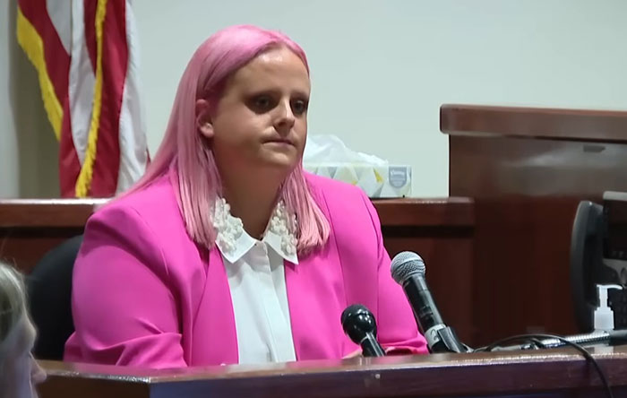 Woman with pink hair and pink blazer speaking in court, related to Athena Strand&rsquo;s mom attending every court date.