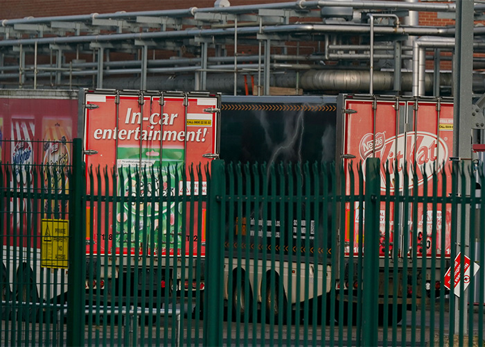 KitKat delivery truck behind a green fence at an industrial site related to stolen KitKat tracker efforts.