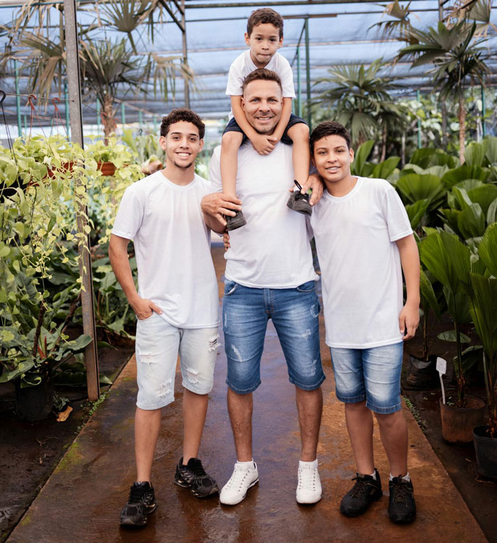 A happy family of men and boys in white shirts and denim shorts in a plant nursery. Man demands paternity test.