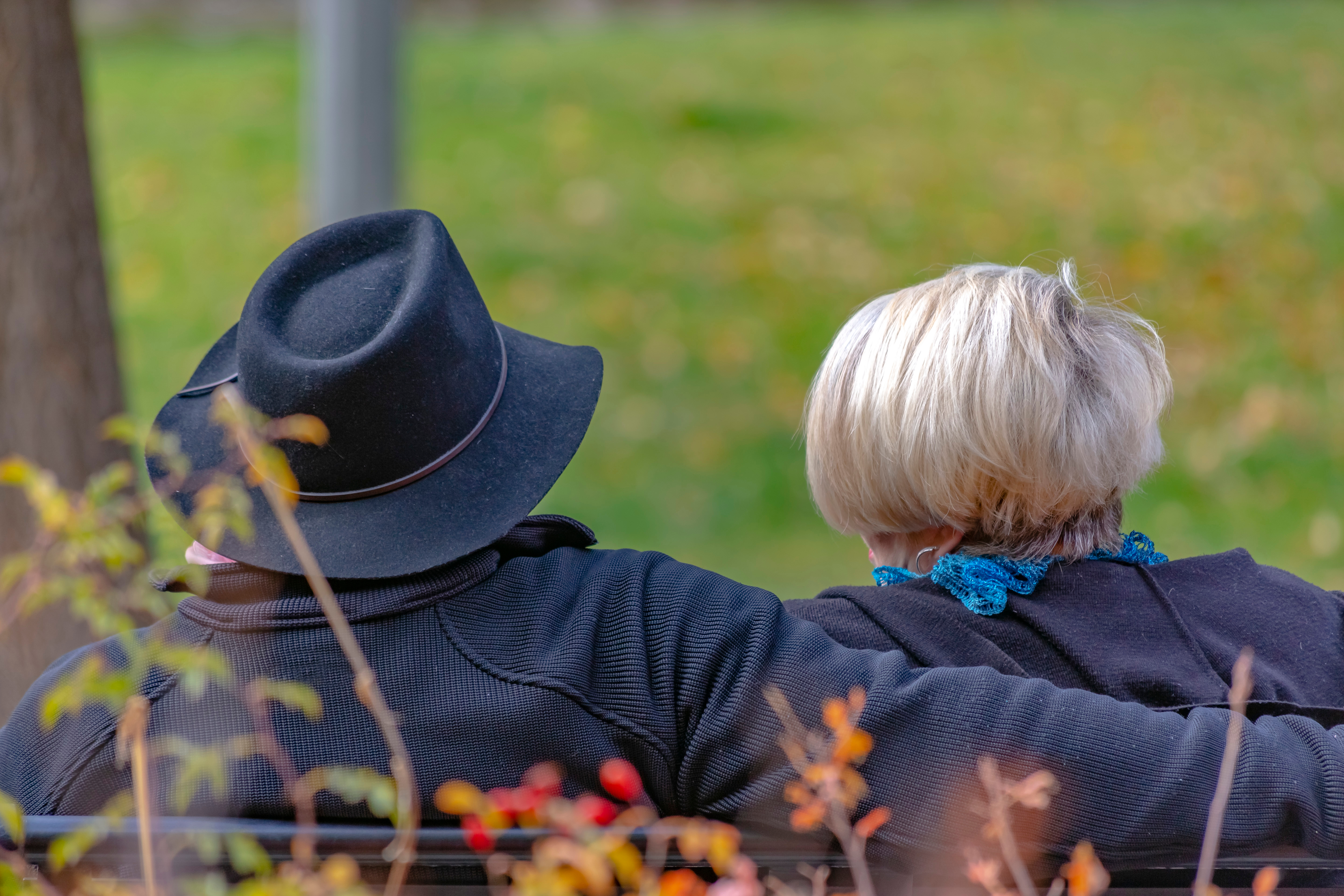 Two people sitting closely on a park bench, illustrating a man confronting parents about 20YO best friend controlling behavior.