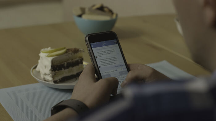A person views a cheating story on their phone while a slice of cake sits beside them.