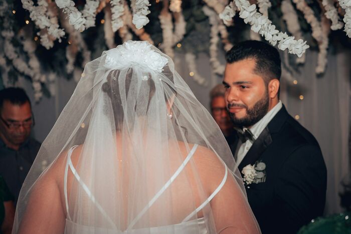 Bride wearing a veil and groom in a suit under floral wedding decorations, illustrating trashy wedding stories.