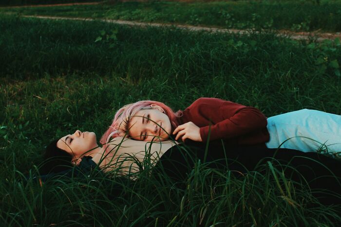Two people lying on grass, peacefully resting, illustrating how random life decisions can lead to the right place.