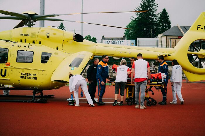 Emergency medical team loading patient into yellow rescue helicopter, highlighting jobs AI can’t replace in healthcare.