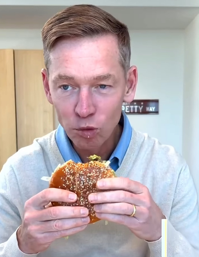 McDonald&rsquo;s CEO tasting a Big Arch burger, reacting to the viral sandwich with a focused expression indoors.