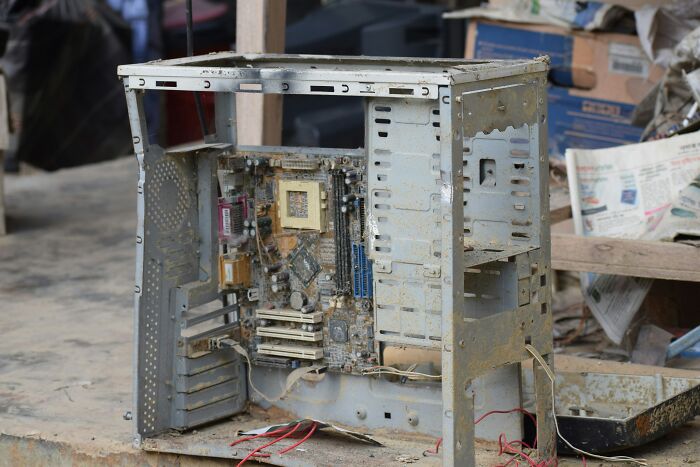 A severely damaged and dirty computer casing with exposed motherboard, highlighting the aftermath of workplace incidents.