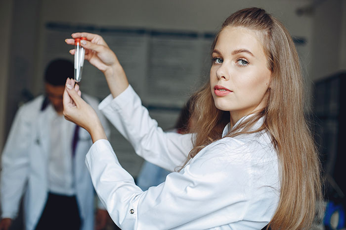 Female scientist in a lab coat holding a DNA test tube, illustrating drama over confusing family dynamic and child support.