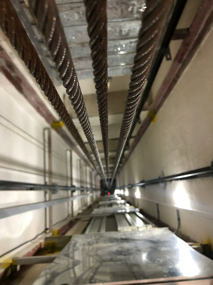 POV looking down an elevator shaft with multiple thick cables, illustrating a potential workplace incident.