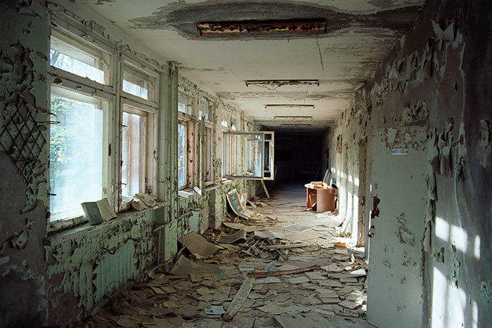 Abandoned and decaying hallway with peeling walls and scattered debris illustrating historical mistakes with massive consequences.