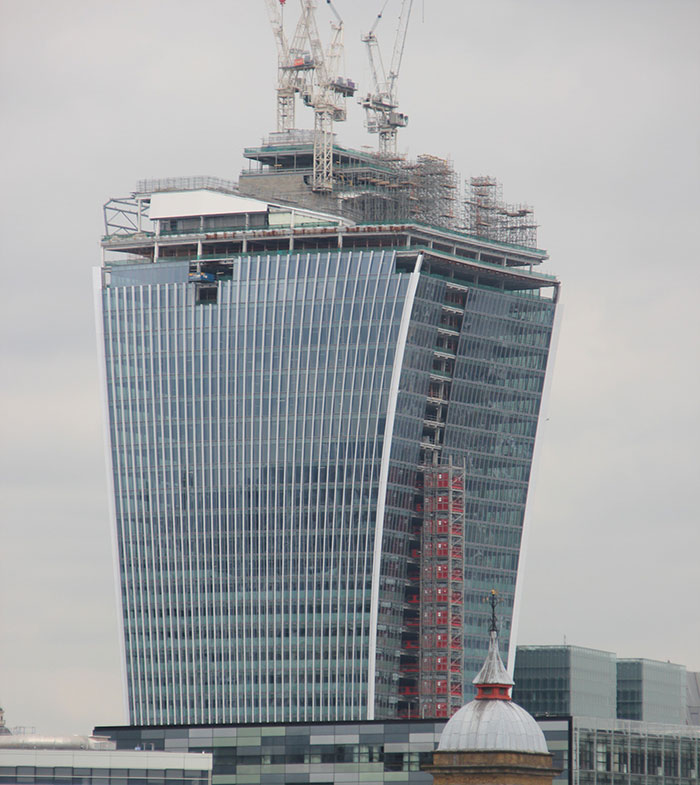 Modern skyscraper under construction with cranes, illustrating historical mistakes with massive costly consequences.