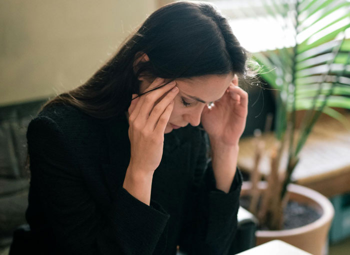 Mulher enfrentando um dilema, estressada e pensativa, sobre a mãe controlar seu arranjo de dormir com a futura esposa.
