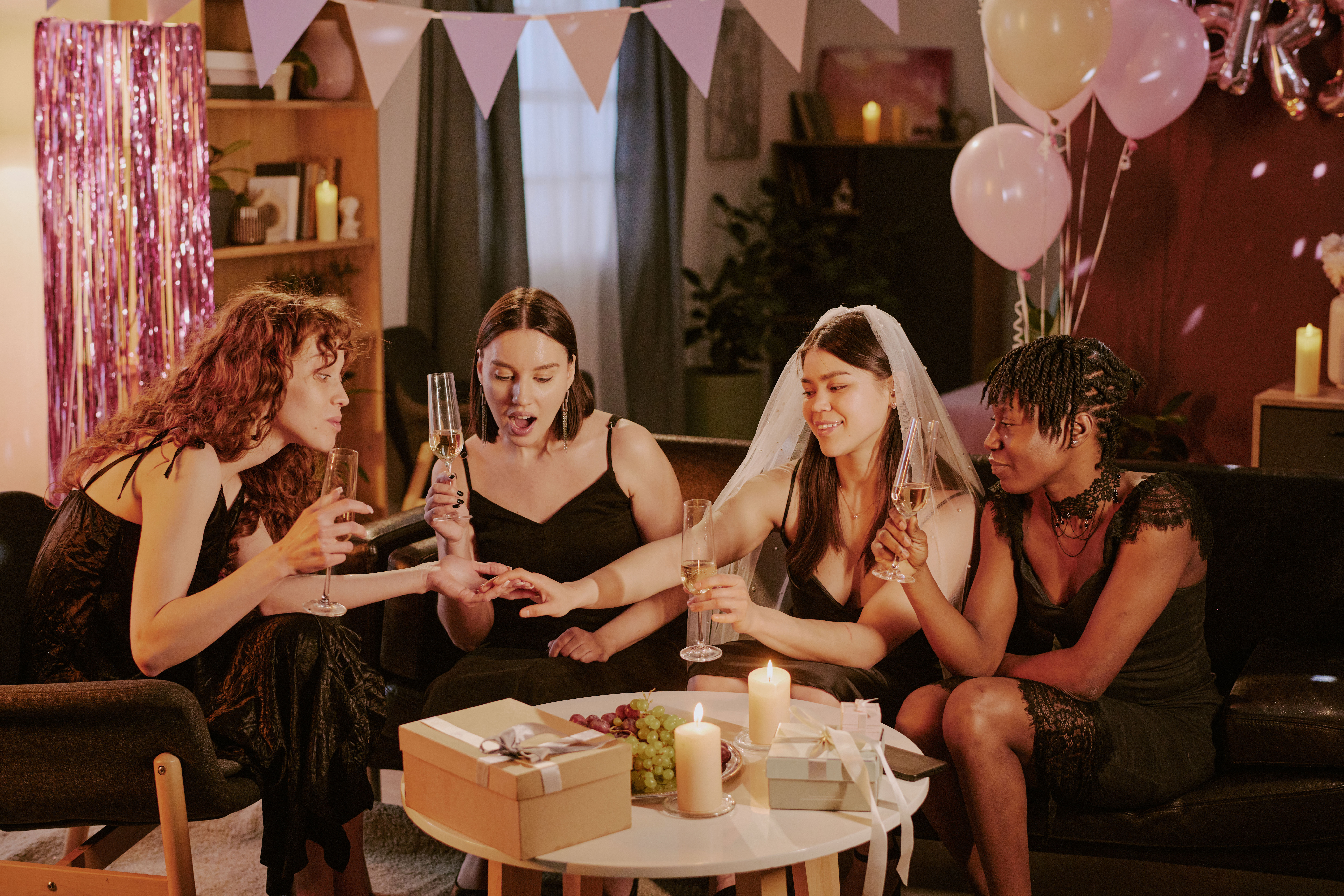 Four friends celebrating at a party, one showing off a ring. Best friend skips wedding, breaking the bride's heart.