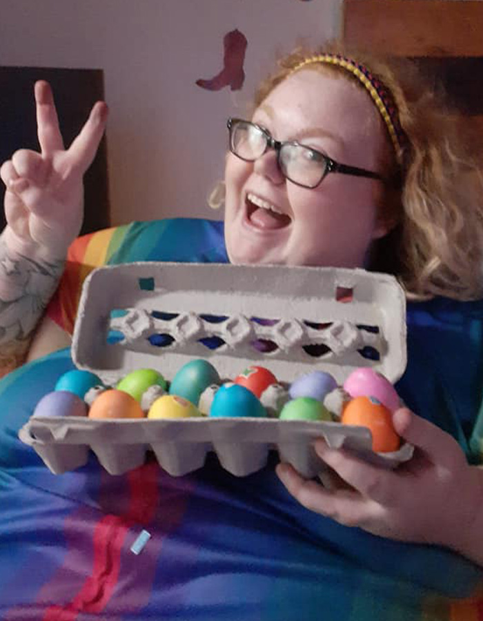 Dolly Martinez from My 600-Lb. Life smiling and holding a carton of colorful Easter eggs while making a peace sign.