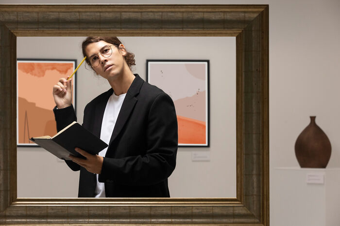 A pensive person in glasses, holding a notebook and pencil, framed by a border. They reflect on narcissists.