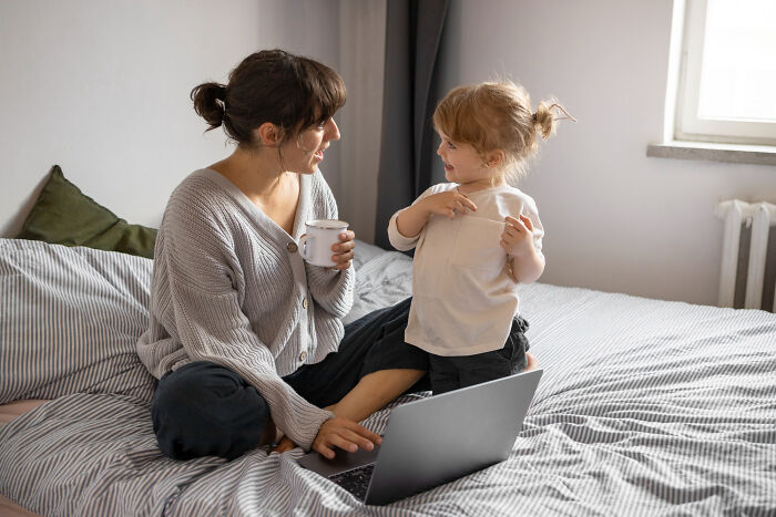 A mother and child on a bed with a laptop, sharing a moment. This image relates to how narcissists leave a mark.