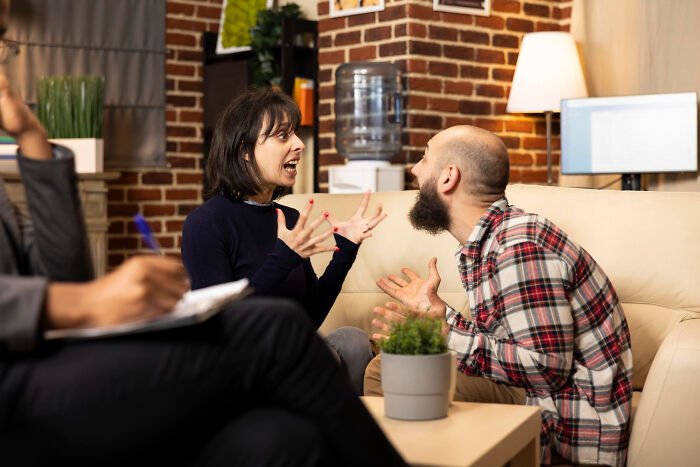 A couple arguing heatedly on a couch during therapy, with the woman gesturing emphatically. This highlights how diagnosed narcissists leave a mark.