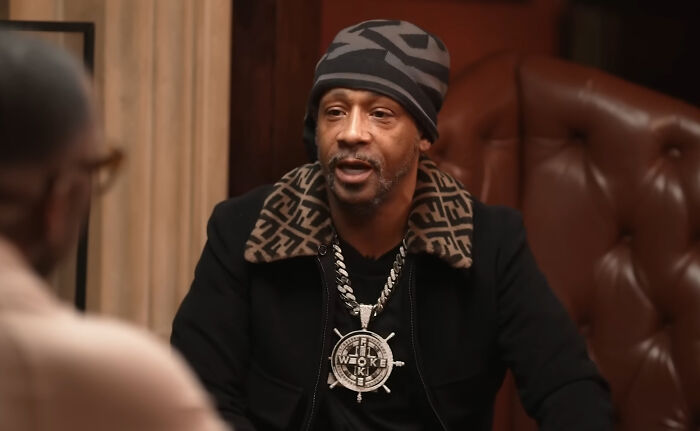 A man in a beanie and Fendi collar, wearing a large WOKE pendant, talking about rudest celebs.