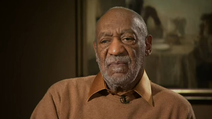 A close-up of Bill Cosby, an aging Black man with a beard, wearing a brown sweater, from the rudest celebs list.