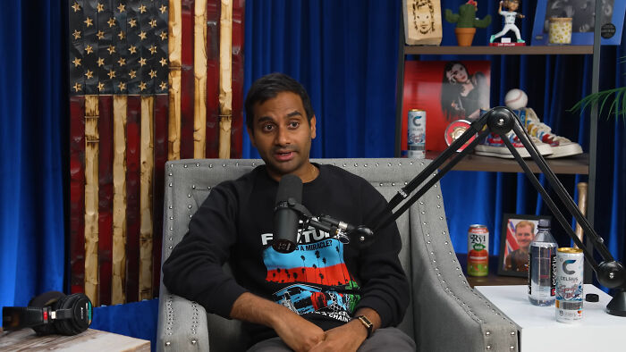 Aziz Ansari speaks into a microphone, sitting in a studded chair. He's one of the rudest celebs, according to folks.