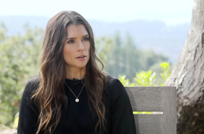 A woman with long brown hair and a black top, outdoors, could be one of the rudest celebs.