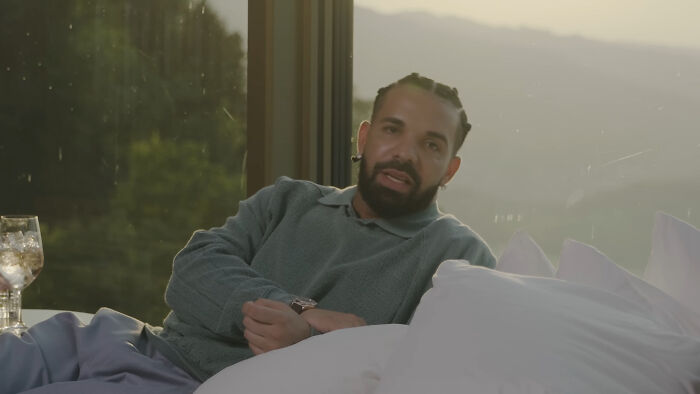 Drake, a prominent celeb, lounges on a bed, looking relaxed. He's one of the rudest celebs many have encountered.