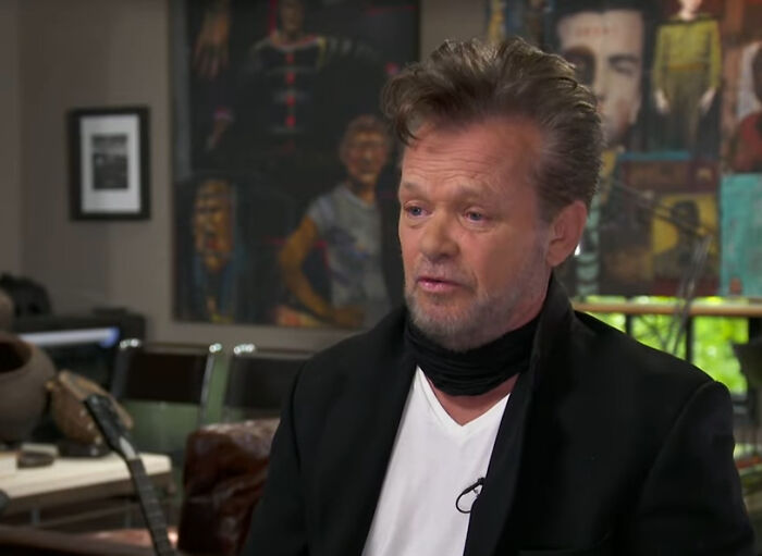 A male celebrity with a beard and dark hair, wearing a white shirt and black blazer, with artwork in the background. Folks discuss rudest celebs.