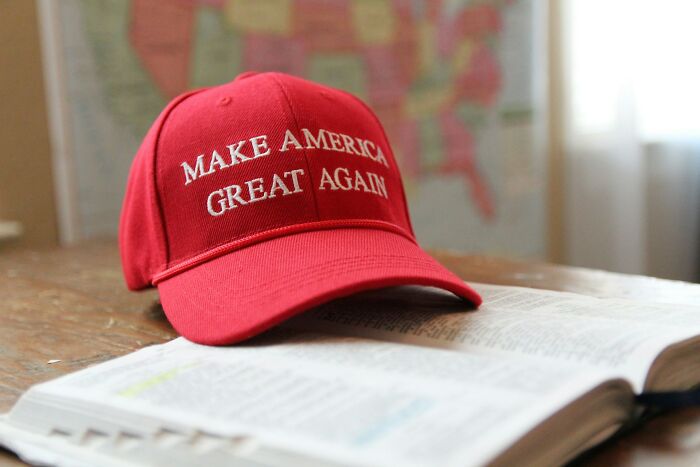 Red Make America Great Again hat resting on an open book, illustrating resilience in stories of horrible bullies.