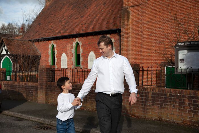 Young adult and child walking outside near brick building, illustrating story about prisoner pen pal and neighbor dispute.