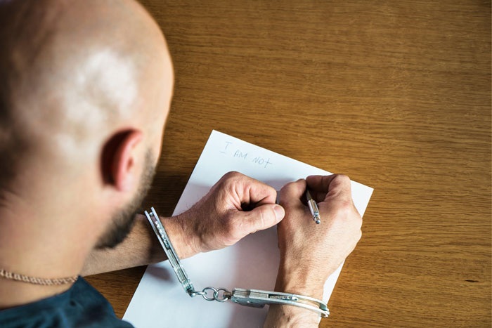 Man in handcuffs writing a letter on behalf of rude neighbor pretending to be gay in a prisoner pen pal scenario