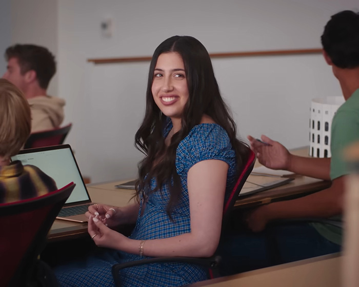 Young woman smiling while seated in a classroom setting, part of Netflix's new comedy sparking nepotism backlash.
