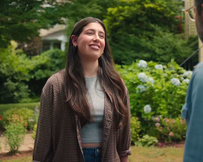 Young woman smiling outdoors in a garden setting, representing Netflix's new comedy sparking nepotism backlash.