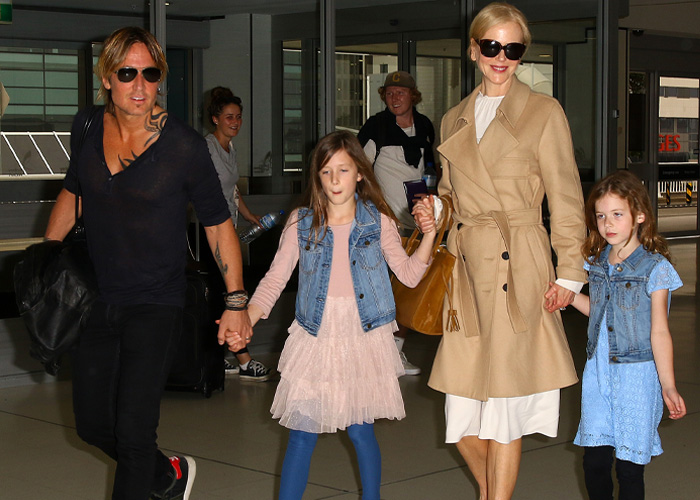 Nicole Kidman wearing a beige trench coat and sunglasses walking with family, sparking reactions with her sheer look.