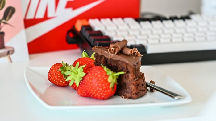 Chocolate cake slice with strawberries, a Nike box, and a keyboard in the background. Illustrates why people rage quit their jobs.