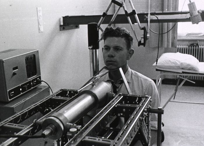 Man undergoing early medical device treatment involving mechanical apparatus in a black and white vintage healthcare setting