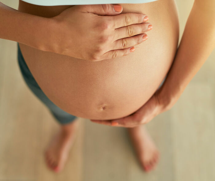 Pregnant woman gently holding her belly, representing pregnant doctor showing baby peeing inside the womb concept.